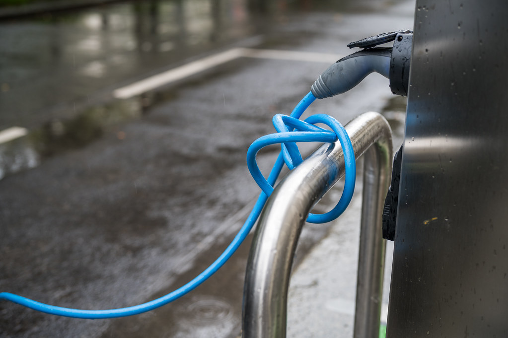 Câble de recharge bleu pour voiture électrique branché sur une borne de recharge extérieure.