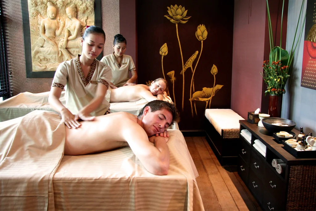 Massage en duo dans une cabine de spa, deux tables de soin côte à côte.