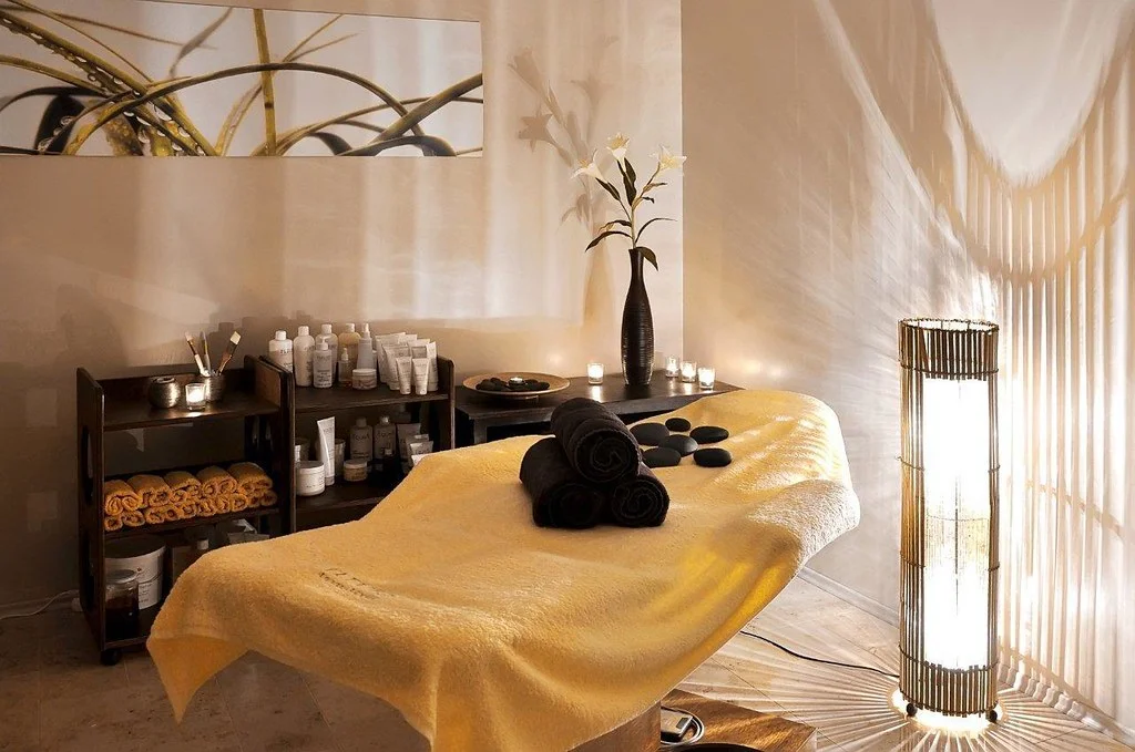 Salle de soin d'un spa de luxe avec table de massage, serviettes roulees et bougies.