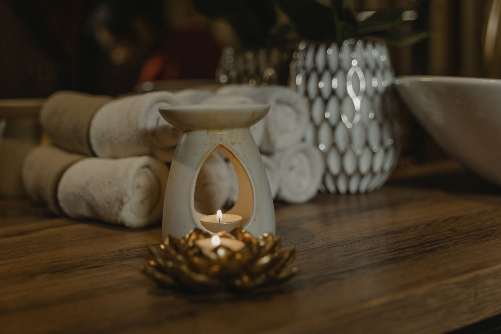 Bougie parfumée, serviettes pliées et objets de décoration sur une table de spa.