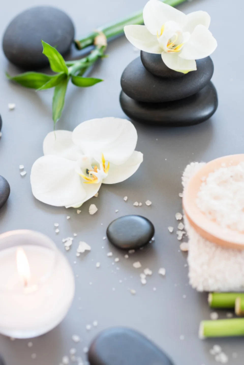 Galets chauds, orchidees blanches, bougie et sels de bain sur une table de spa